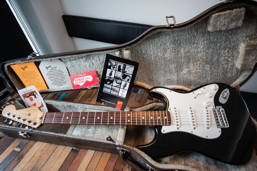 white and black stratocaster electric guitar with case