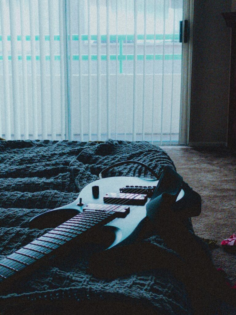 an electric guitar lying on bad in a room